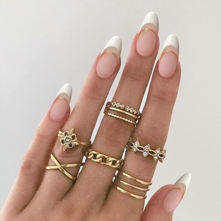 Chic Manicure: Classic French Tips with Modern Nude Base and Gold Accents.