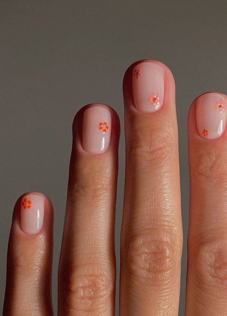 Charming Floral Nail Design: Soft Peach Base with Playful Orange Accents for Spring.