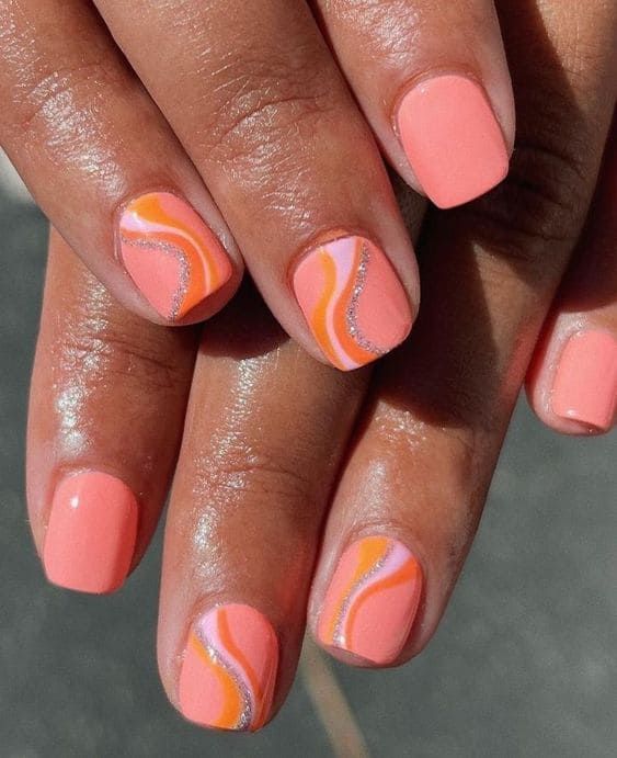 Playful Coral Nail Design: Vibrant Peach Base with Orange and White Accents, Sparkling Glitter for Glamour.