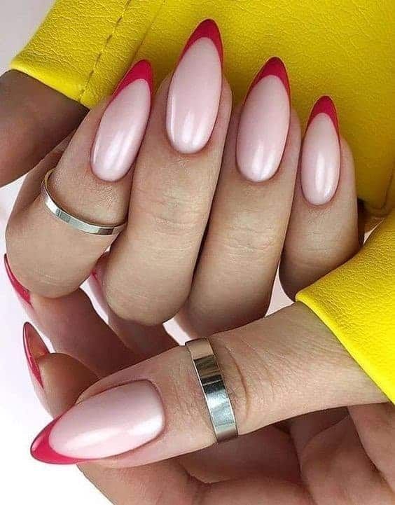 Chic Almond-Shaped Nails: Elegant Nude Base with Striking Red Tips and Minimalist Accessories.