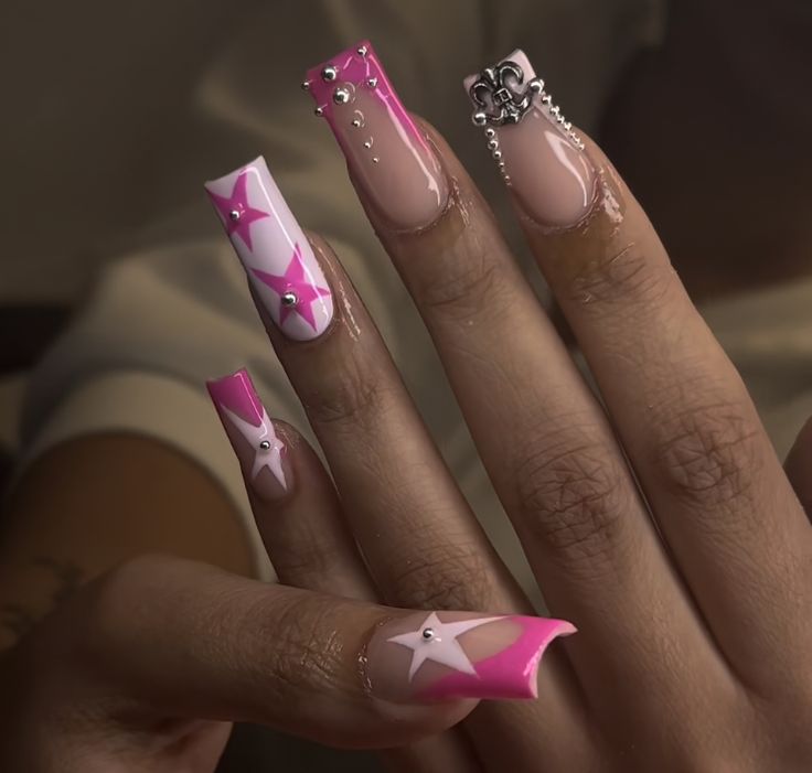 Playful Vibrant Nail Design with Elongated Tips, Bold Pink Accents, and Glamorous Star Motifs.