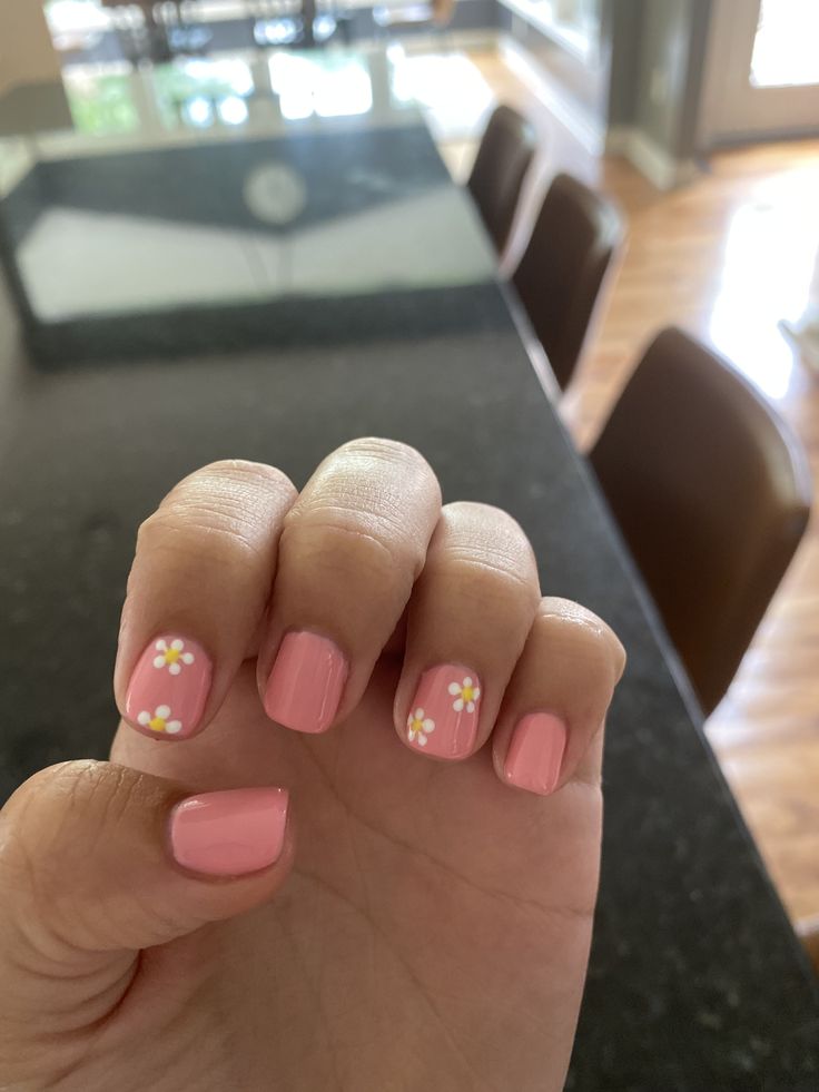 Whimsical Soft Pink Nail Design with Delicate White Flower Accents for a Fresh Spring/Summer Look.