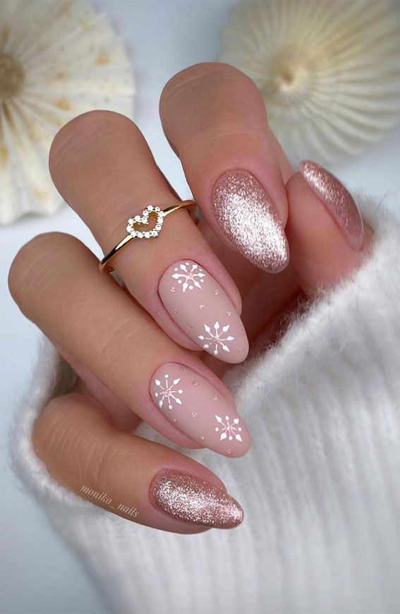 Chic Winter Nail Design: Nude Base with White Snowflakes and Rose Gold Glitter Accents.