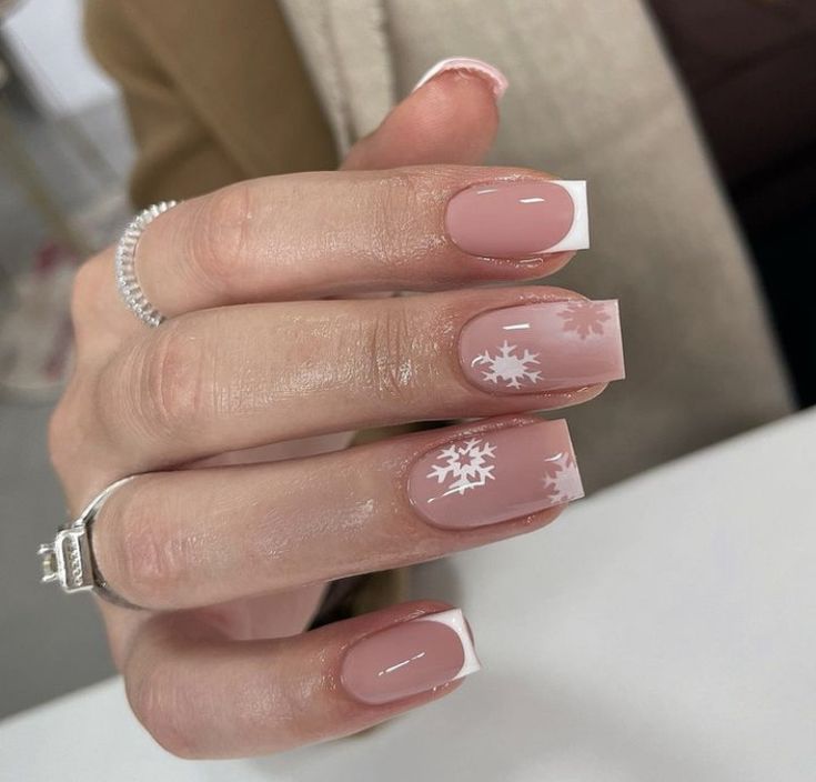 Chic Winter Nail Design: Nude Base with Classic White Tips and Elegant Snowflake Motifs.