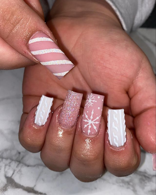 Playful Winter-Themed Nail Art: Striped and Glittery Patterns on a Pastel Pink Base.