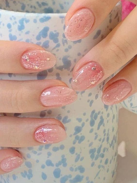 Elegant Soft Pink Gradient Nails with Glitter and Shimmer Finishes.