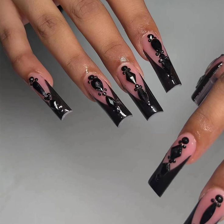 Luxurious Long Tapered Nail Design with Glossy Black Accents and Intricate Embellishments on a Nude Base.