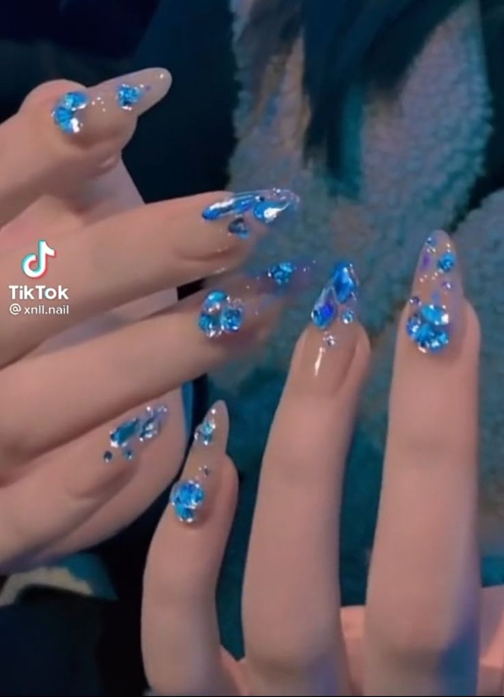 Glamorous Translucent Nail Design with Sparkling Blue Crystals for Elegance and Fun.