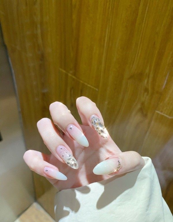 Chic Almond-Shaped Nail Design with Gradient, Gold Accents, and Rhinestones for Effortless Glamour.