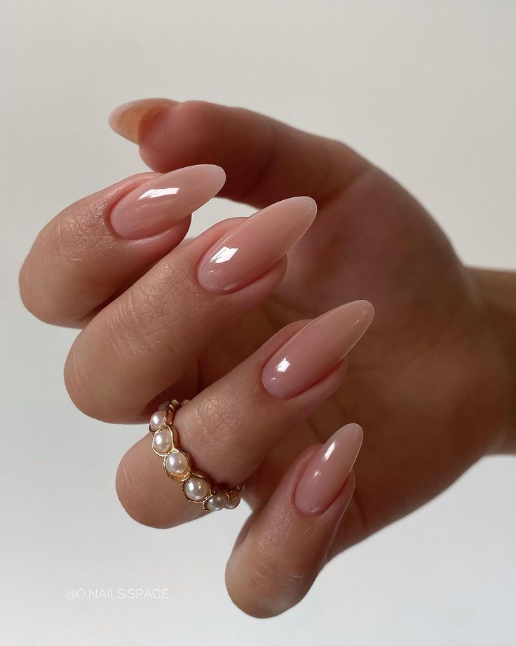 Elegant Almond-Shaped Nails in Nude and Soft Pink with Glossy Finish and Pearl Ring Enhance Sophisticated Style.