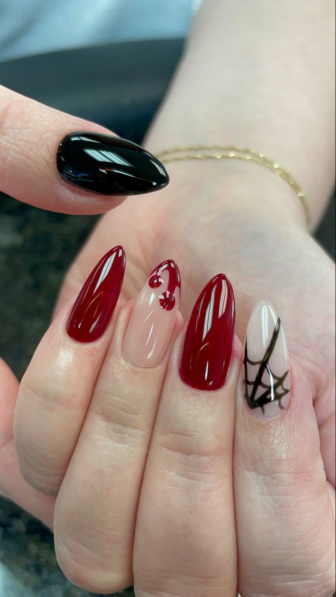 Sophisticated Nail Art: Deep Red, Nude, and Glossy Black with Playful Patterns and Spider Web Motif.