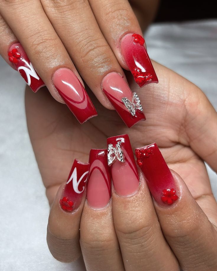 Elegant Red Nail Design with Glossy and Matte Finishes, Rhinestones, Flowers, and Metallic Butterfly Accents.