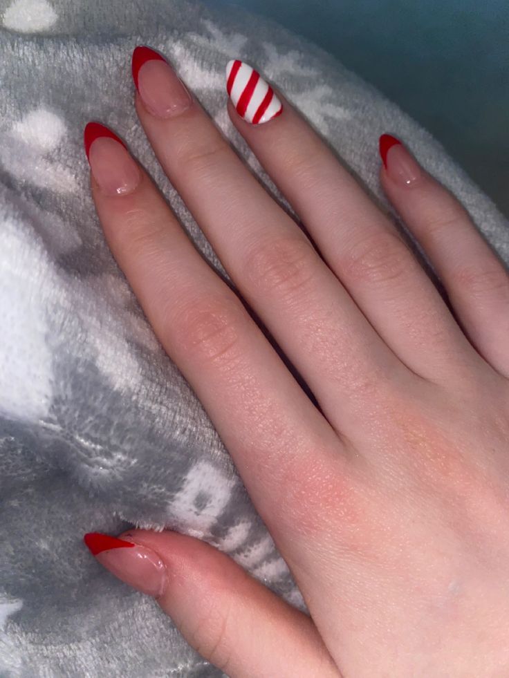 Cheerful Festive Nail Design: Bold Red Tips with Playful Striped Accent.