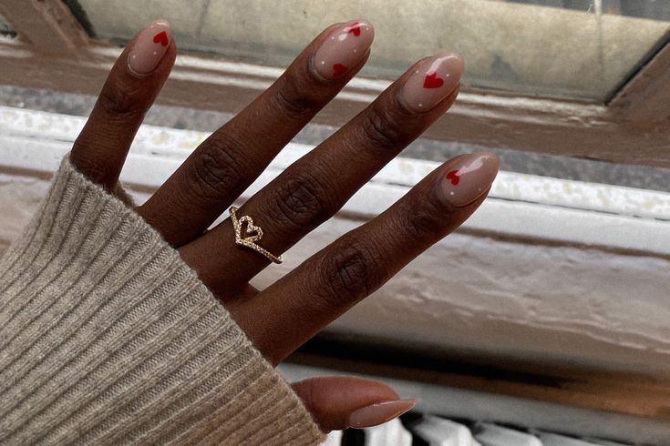 Chic Nude Nail Design with Striking Red Heart Accents for Playful Elegance.