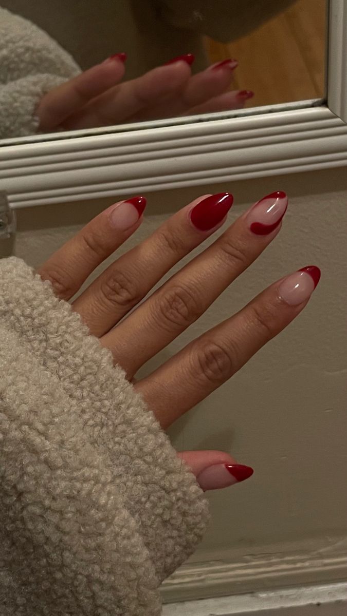 Chic Nail Design: Bold Red and Nude French Tips with Whimsical Heart Accent.