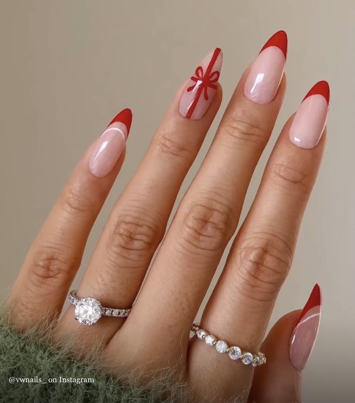 Chic French Manicure: Soft Pink Base with Striking Red Tips and Festive Ribbon Accent.