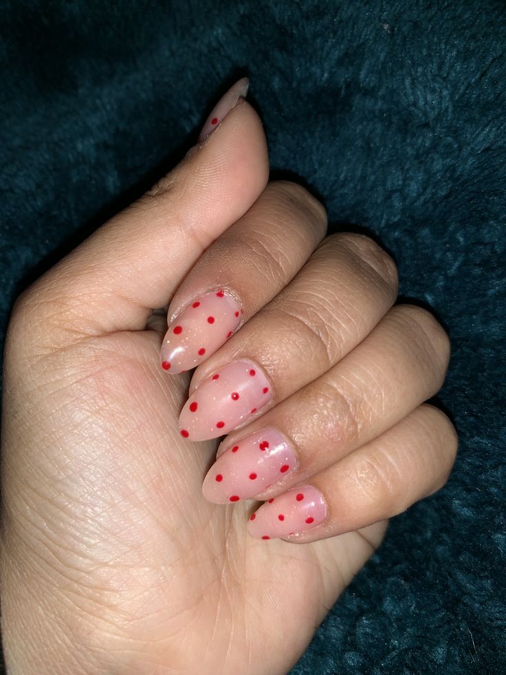 Playful Polka Dot Nail Design: Sophisticated Almond Shape with Soft Nude Base and Bright Red Dots.