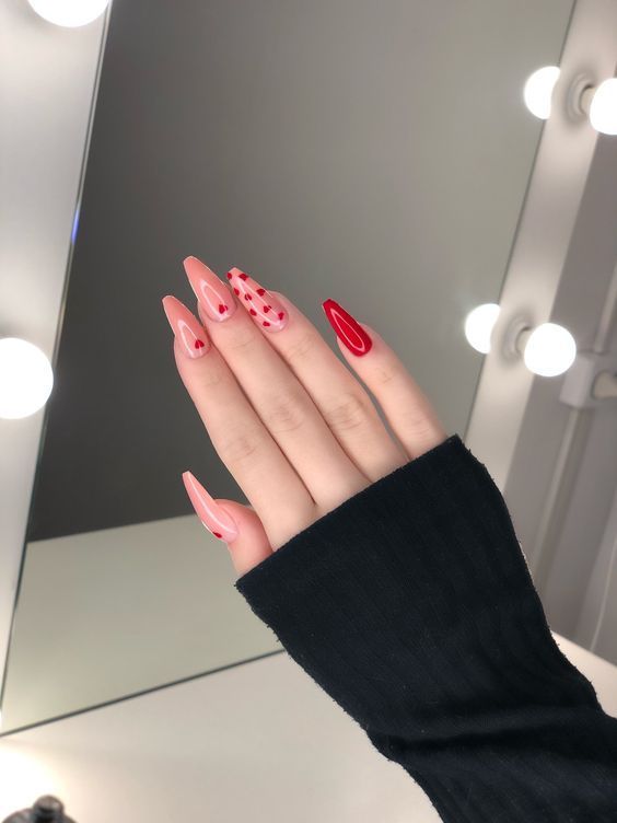 Vibrant Stiletto Nail Design: A Bold Red and Soft Pink Contrast with Playful Dot Patterns.