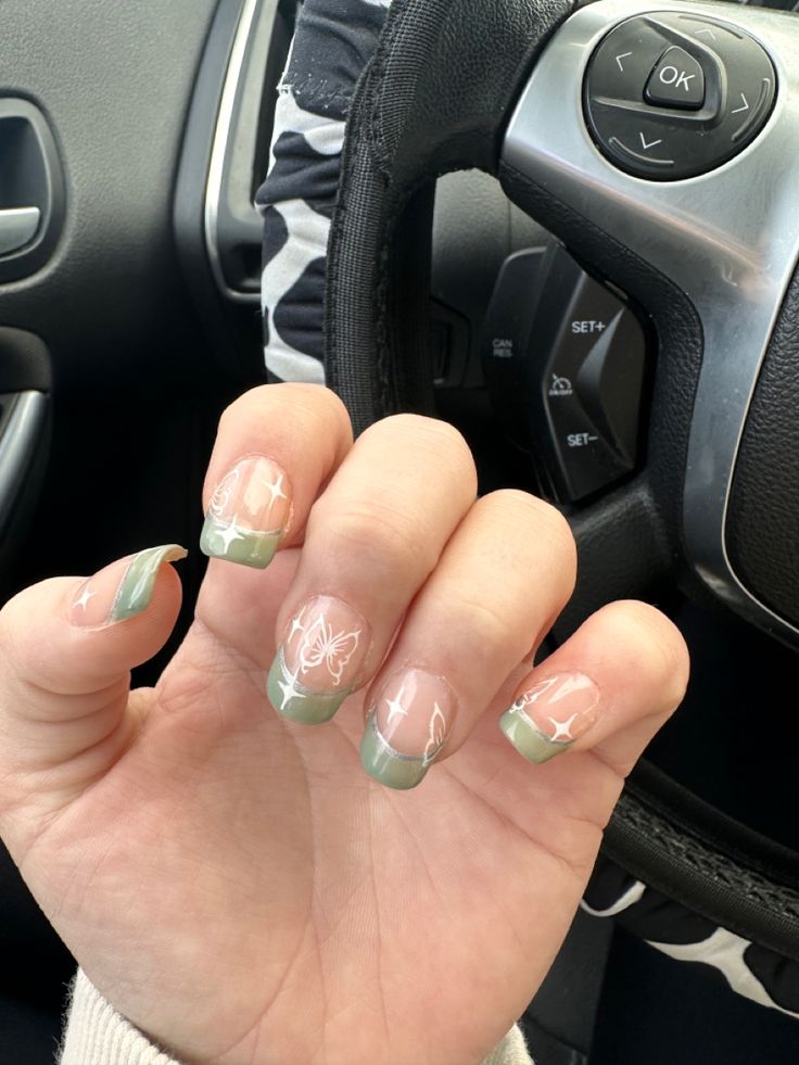 Charming Soft Green French Tip Nails with Delicate White Floral Patterns.