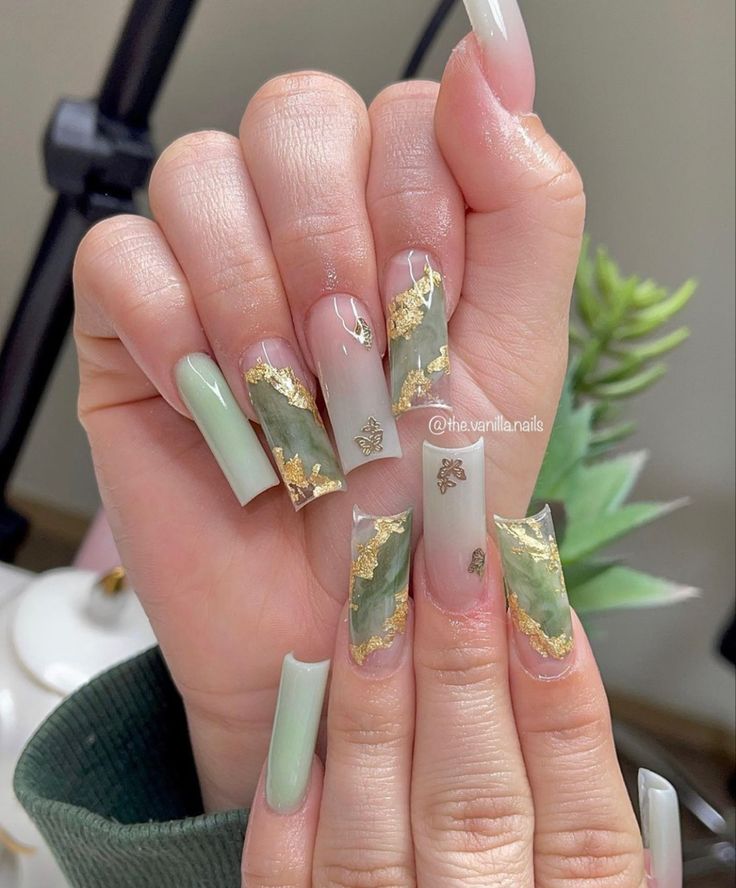 Elegant Elongated Tip Nail Design: A Sophisticated Blend of Soft Greens, Leaf Patterns, and Gold Accents.