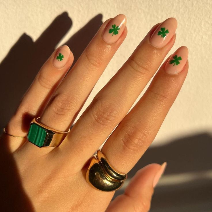 Elegant Nude Nails with Charming Green Clover Designs and Gold Rings