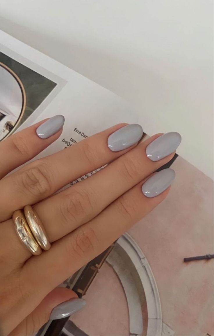 Elegant Oval Nails in Soft Grey with Glossy Finish and Complementary Gold Rings.