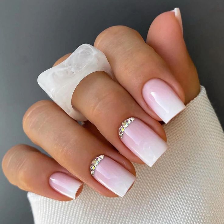 Sophisticated Ombre Nails: Pale Pink to White Gradient with Rhinestone Accents.