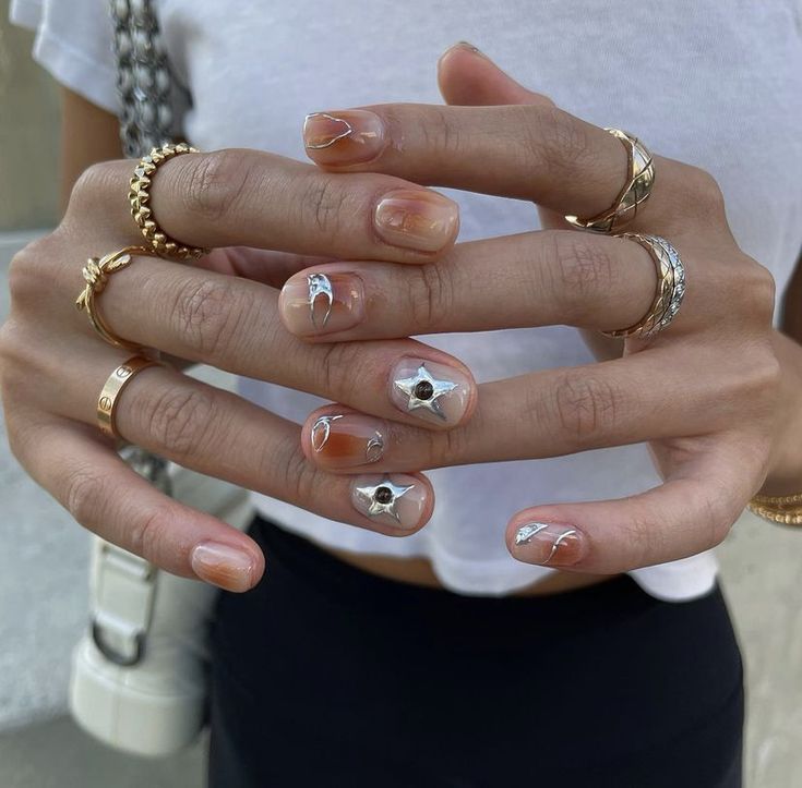 Sophisticated Nail Design with Nude Polish, Star Accents, and Glamorous Ring Styling.