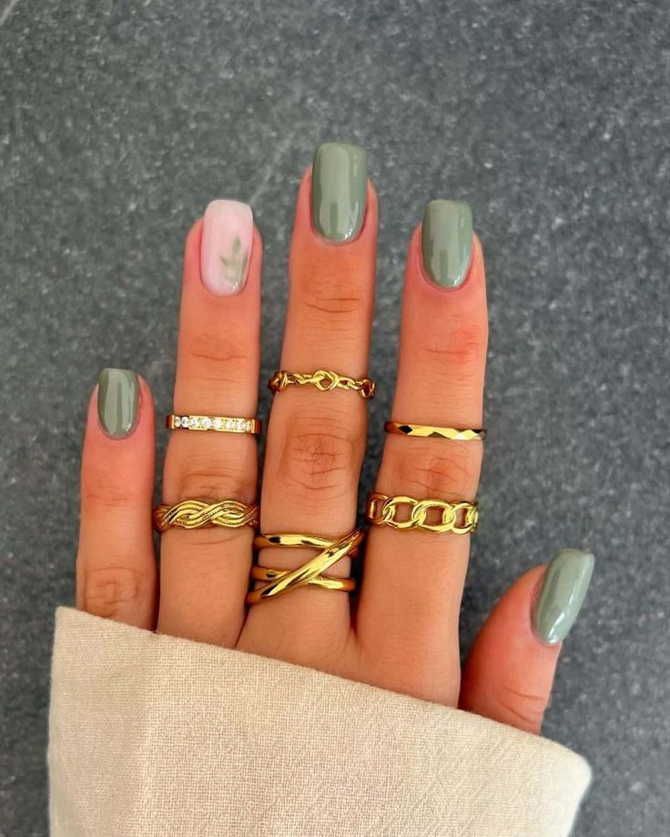 Chic Olive Green Nail Design with Floral Accent and Gold Rings for Sophisticated Elegance.