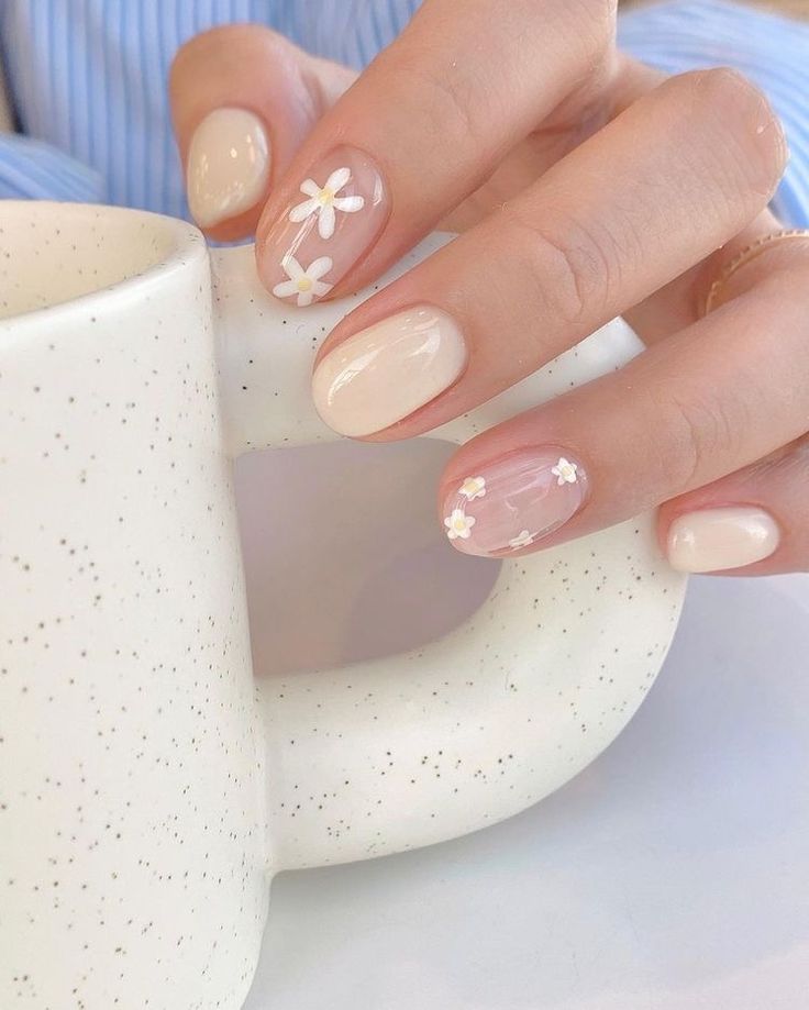 Elegant Floral Nail Design: Soft Nude Base with Delicate White Daisies for a Chic, Playful Look.