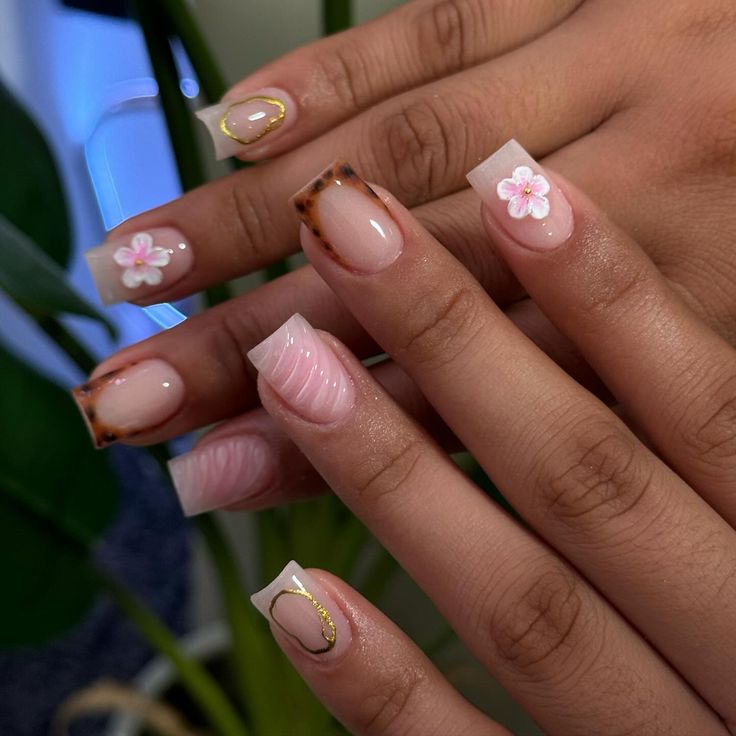 Chic Floral Nail Design with Soft Pinks, Clear Tips, and Golden Accents.