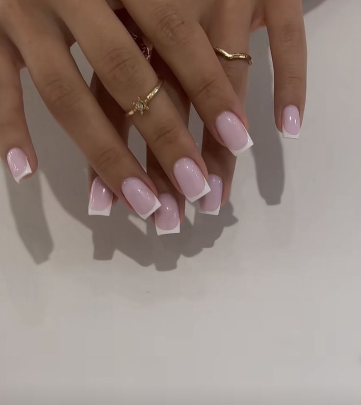 Sophisticated Soft Pink and White Tip Manicure with Elegant Ring Accents.