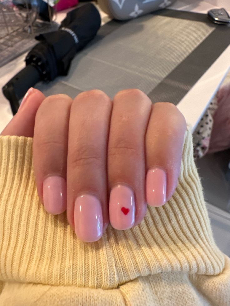 Chic Soft Pink Nail Design with Playful Red Heart Accent.