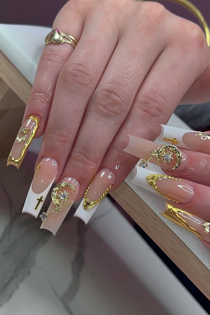 Elegant Nail Design: Elongated Nude and White Tips with Gold Accents and Intricate Motifs.