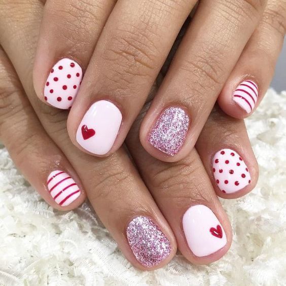 Playful Pink Nail Design with Festive Patterns and Glamorous Glitter Accents