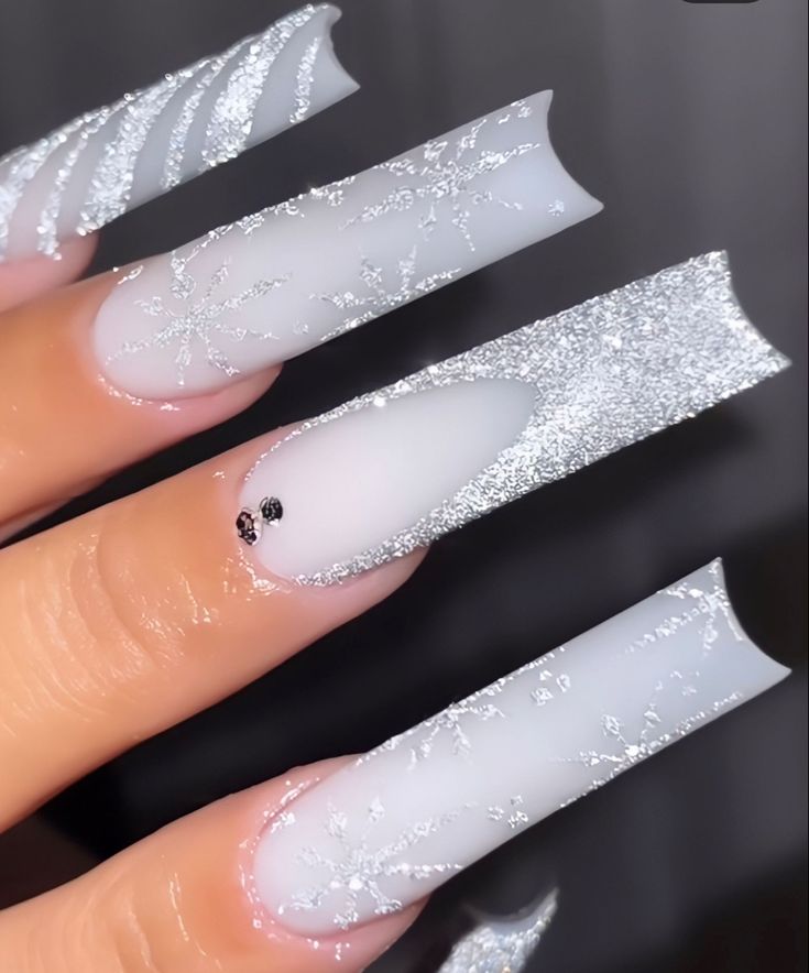 Elegant Winter-Inspired Nail Art: Frosty White and Shimmering Silver with Intricate Snowflake Patterns.