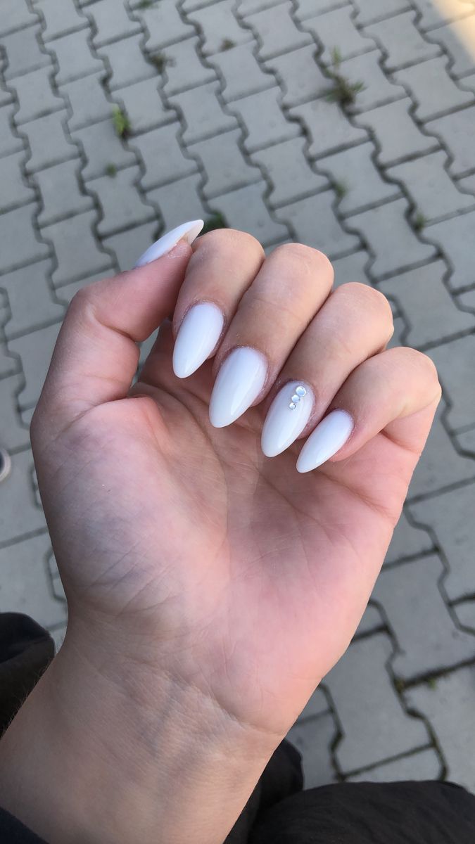 Chic Almond-Shaped White Nails with Gemstone Accents for a Sophisticated Look.