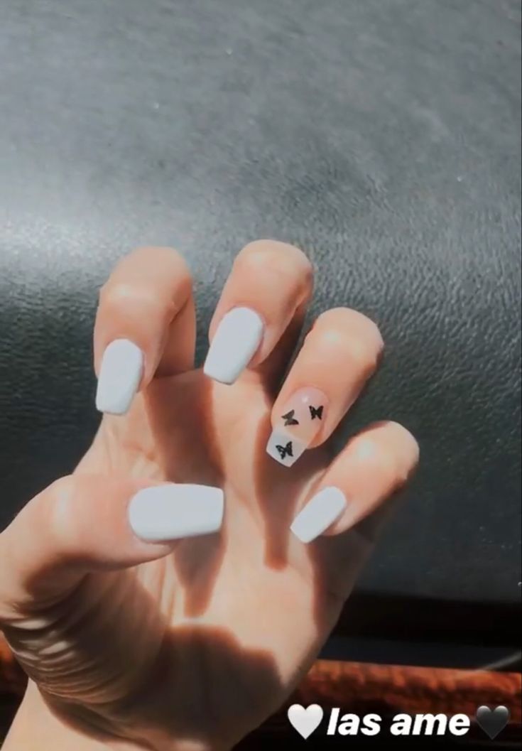 Elegant White Nails with Playful Black Butterfly Accents for a Versatile Look.