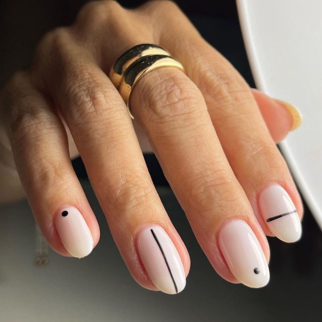 Elegant Minimalist Nail Design with Soft Nude Base and Geometric Black Accents, Enhanced by a Gold Ring.