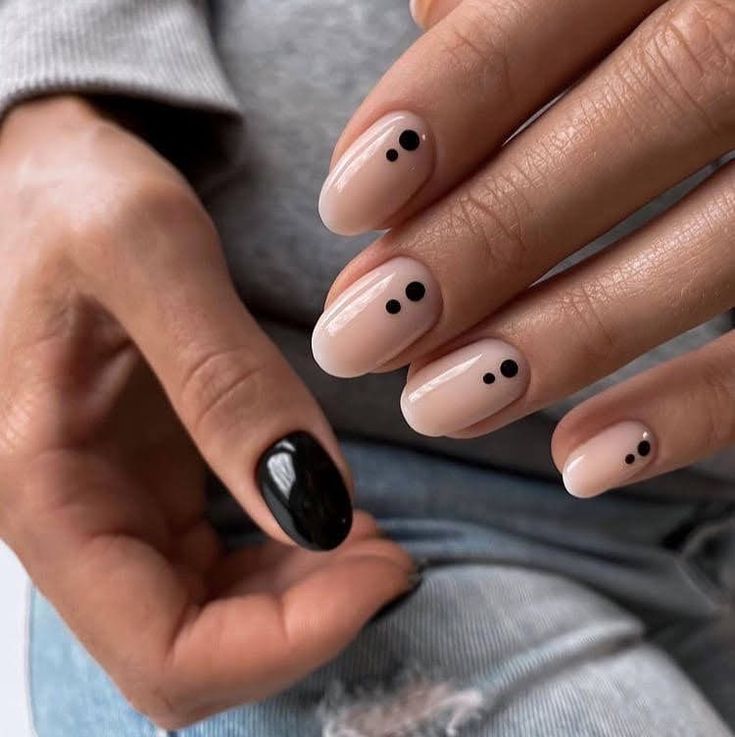 Chic Minimalist Nail Design: Nude Base with Dot Patterns and Bold Black Accent.