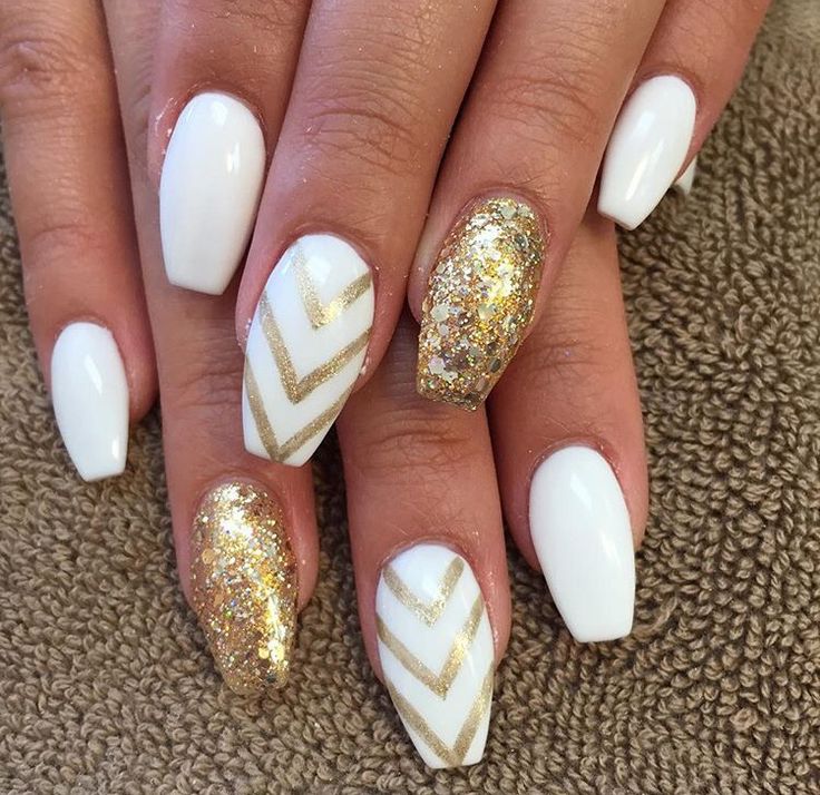 Chic Glossy White and Shimmering Gold Nail Design with Chevron Accents.