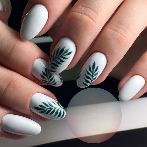 Sophisticated Nail Design: Glossy White Base with Delicate Green Leaf Patterns.