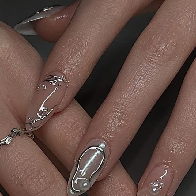 Elegant Almond-Shaped Nail Design with Translucent and Silver Tones Enhanced by Intricate Patterns