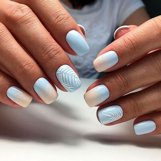 Chic Blue Ombre Nail Design with Elegant White Leaf Accents.