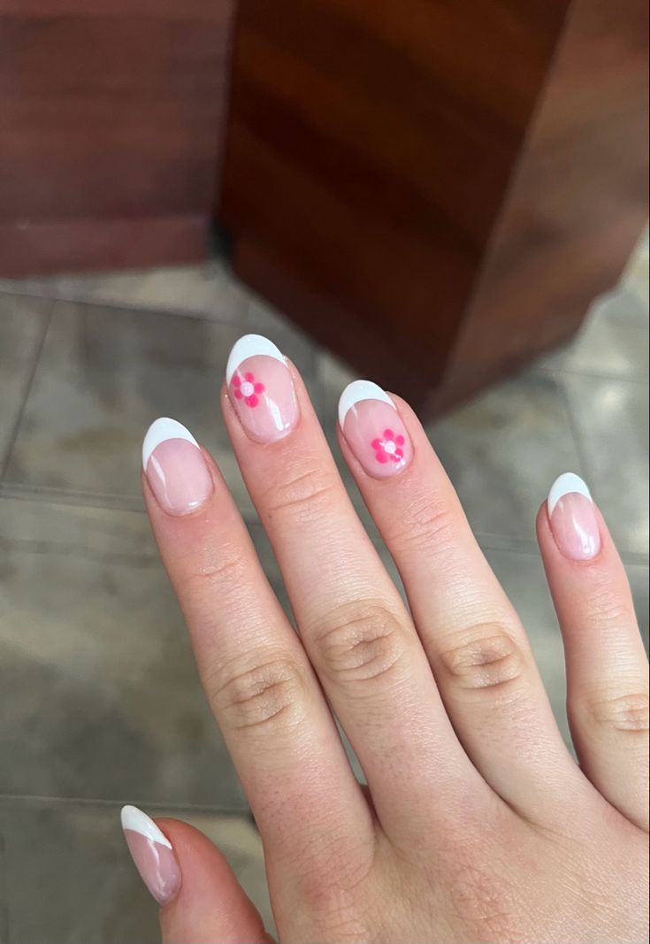 Charming French Manicure with Hand-Painted Floral Accents: A Blend of Sophistication and Playfulness.