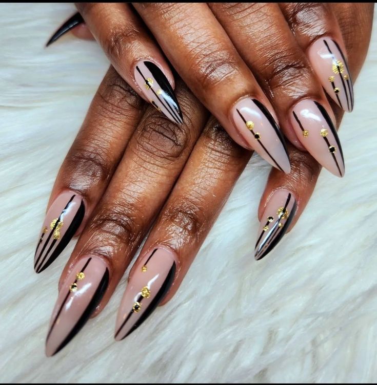 Sophisticated Almond Nail Design with Nude, Black, and Golden Accents.