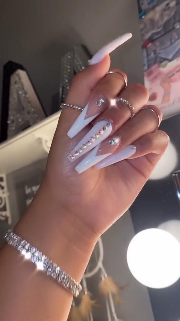 Elegant Glossy White Stiletto Nails with Rhinestone Accents and Geometric Patterns.