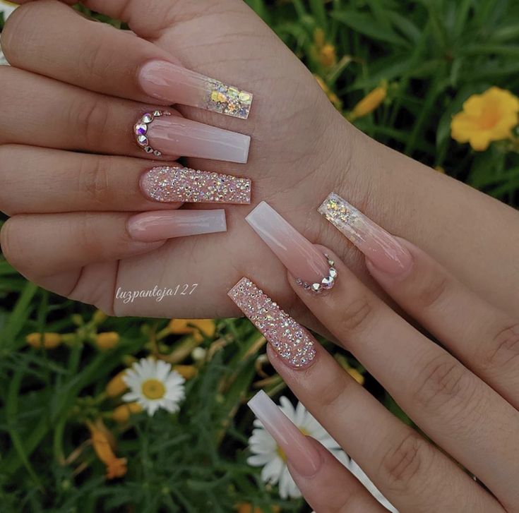 Elegant Nude and Glitter Nail Design with Floral Accents and Rhinestone Details.