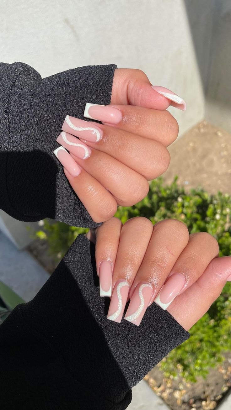 Chic Soft Pink and White Tip Nail Design with Modern Swirling Accents.