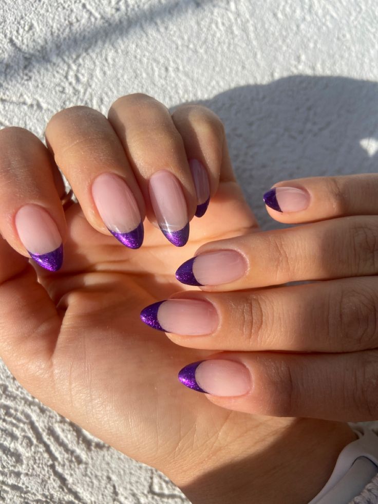 Trendy Nail Design: Soft Nude Base with Bold Purple Glitter Tips for a Modern Twist on French Manicure.